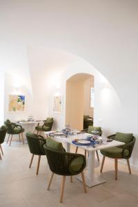 a dining room with white tables and green chairs at PALAZZO SAN ROCCO in Sperlonga
