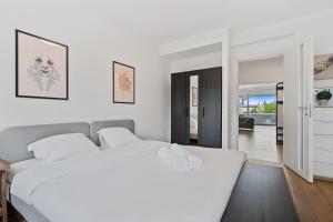 a white bedroom with a large bed and a living room at Central Lux 2BR Apt with City Views & Balcony in Luxembourg