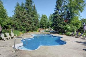 a swimming pool in a yard with chairs and a table at Tremblant Classic Chalet La Bête Golf Course in Mont-Tremblant