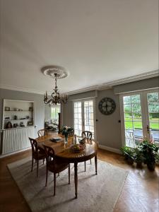 a dining room with a table and chairs and a clock at les Tulipes in Antrain