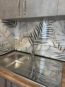 a stainless steel sink in a kitchen with a wallpaper at Bejart Apartment 6 in Tirana