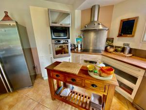 una cocina con una mesa en el medio. en Maison 6p, 3ch, piscine, jacuzzi, cuisine d'été, jardin clos, en Alba La Romaine