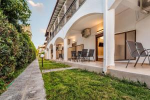 a view of a building with chairs and grass at Odyssey Accommodation - Apartments in Pefkochori