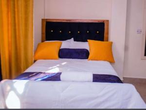a bed with orange and blue pillows on it at Kamiri Comfort in Embu