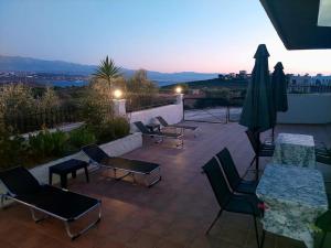 Un patio con sillas y mesas y una sombrilla. en Iakovos apartments, en Chorafakia