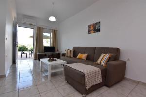 Una sala de estar con un sofá marrón y una mesa. en Iakovos apartments, en Chorafakia