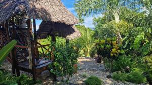 a garden with a bench and a straw hut at Villa ecolodge sur l ile de nosy komba in Nosy Komba