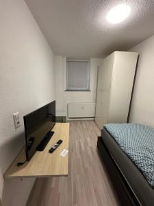 a room with a bed and a desk with a television at Montör und Studentenzimmer Bett Vermietung UG1 in Geislingen an der Steige