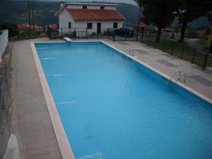 a large blue swimming pool in front of a house at Casa do avô Serafim in Cetos