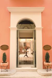 um arco que conduz a uma sala com uma parede cor-de-rosa em Hotel Ippoliti em Nafplio