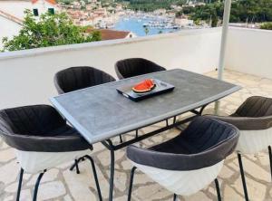 una mesa con sillas y un plato de comida en el balcón en Villa Brazza, en Milna