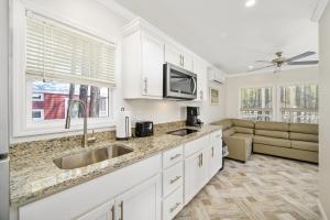 a kitchen with white cabinets and a sink and a couch at Sun Outdoors Rehoboth Bay in Millsboro