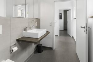 ein weißes Badezimmer mit Waschbecken und Spiegel in der Unterkunft Neubau! Ökologischer Wellnessurlaub in der Eifel in Kopp + 25 Fotos
