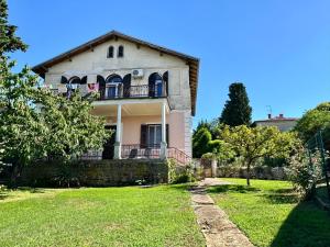 an old house with a green lawn in front of it at Apartma Nona Ana in Izola