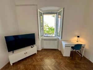 a living room with a flat screen tv and a desk at Apartma Nona Ana in Izola