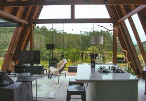 a kitchen and living room with a large window at D'Alma Chalé com café da manhã in Pomerode