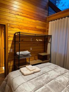 ein Schlafzimmer mit einem Bett mit einer Holzwand in der Unterkunft Cabana Ohana, Espaçosa, Aconchegante e Completa in Urubici