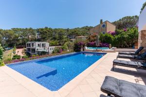 a swimming pool in a yard with two lounge chairs at La Isla in Sa-Riera