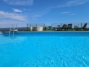 a large blue swimming pool with chairs in the background at Apartamenty przy szlaku in Krajno Pierwsze