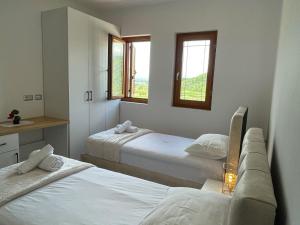 a bedroom with two beds and two windows at Bujtina ALDOR in Berat