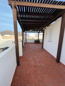 a patio with a brick floor and a wooden pergola at Casa familiar en la almadraba con espectacular terraza in El Pozo del Cabo