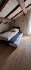 a bed in a room with a wooden floor at Buca 20, tranquillità in  Tassarolo