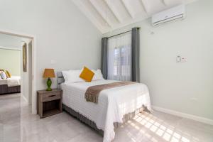 Un dormitorio blanco con una cama y un espejo. en Draxhall Beach Access Gated Community Full Air Con, en Georgia