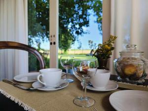 a table with plates and wine glasses on it at B&B Casa del Bosco in San Michele al Tagliamento