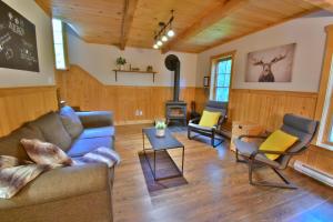 a living room with a couch and chairs and a stove at Nature retreat with HOT TUB and lake access & watercraft in Saint Adolphe D'Howard