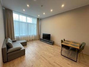 Una sala de estar con un sofá, una mesa y un televisor. en KK apartments, en Liepāja