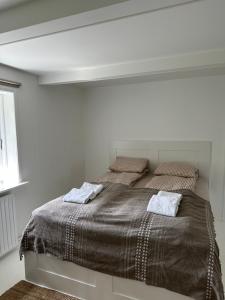 a white bedroom with a large bed with two pillows at Charmerende lejlighed på landet med privat skov in Bjergby