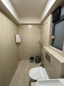 a bathroom with a white toilet and a window at BKC Nest 1BHK Studio Apartment in Mumbai