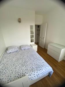 une chambre blanche avec un lit et un miroir dans l'établissement Appartement Saint-Maur-des-Fossés, à Saint-Maur-des-Fossés