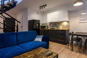 a living room with a blue couch and a kitchen at Osada Podgrzybkowa in Jastrzębia Góra