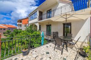 a balcony with a table and an umbrella at Apartman Antonia in Crikvenica