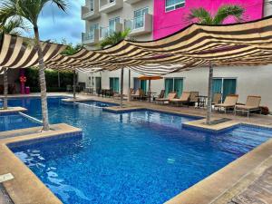 a swimming pool with umbrellas and chairs in front of a building at Hotel Yeah Rinc&oacute;n de Guayabitos in Rincon de Guayabitos