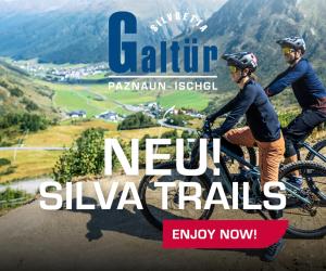two people riding bikes on a mountain road at White Peak in Galtür