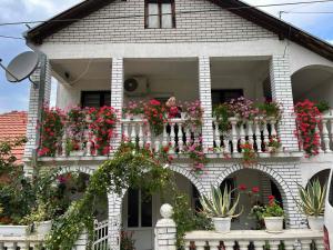 a woman standing on the balcony of a house with flowers at Vila Divna in Tekija