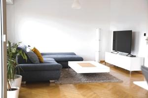 a living room with a blue couch and a tv at Charming Penthouse in the City Center in Luxembourg