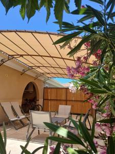 a patio with chairs and awning and a table at Les Villas Maristella, Villa Oriente in Aregno