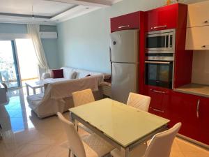 a kitchen with red cabinets and a table with chairs at Azure View Saranda in Sarandë