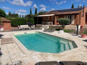 a swimming pool with chairs and a house at La Cigale in Castillon-du-Gard