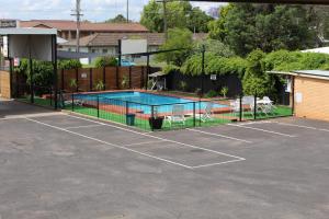 a tennis court with a pool in a parking lot at Golden West Motor Inn in Dubbo