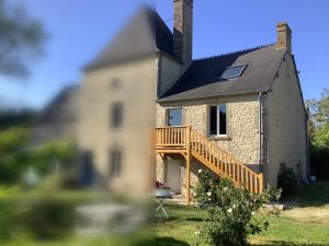 a large brick house with a wooden deck on it at Gîte de la Ressourcery in Sainte-Marie-du-Mont
