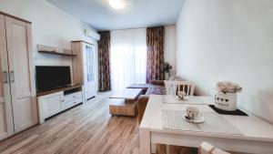 a living room with a table and a tv at Yourhome beach first line in Dobra Voda