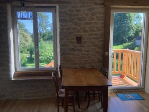a dining room with a wooden table and two windows at Gîte de la Ressourcery in Sainte-Marie-du-Mont