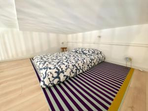 a bedroom with a bed on a striped rug at La mezzanine Rouennaise in Rouen