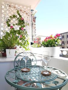 a glass table with two wine glasses on a balcony at Te Amantia Apartment in Tirana
