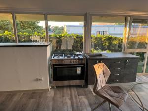 a kitchen with a stove and a counter with a chair at Sico Hostel Centru in Craiova