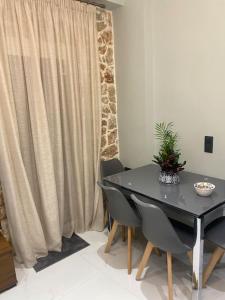 a dining room with a table and chairs and a curtain at Stone house 48 m in Acharnes